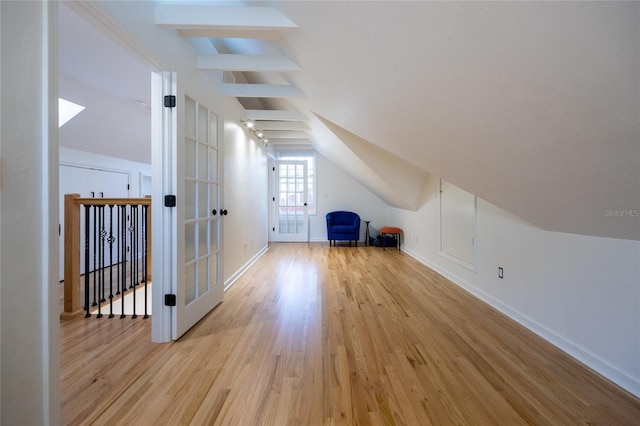 bonus room with light wood-type flooring and vaulted ceiling with beams