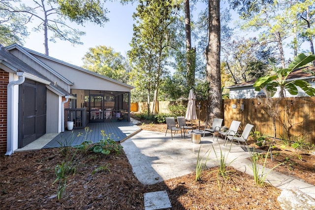 view of patio featuring a fire pit, a sunroom, and a deck