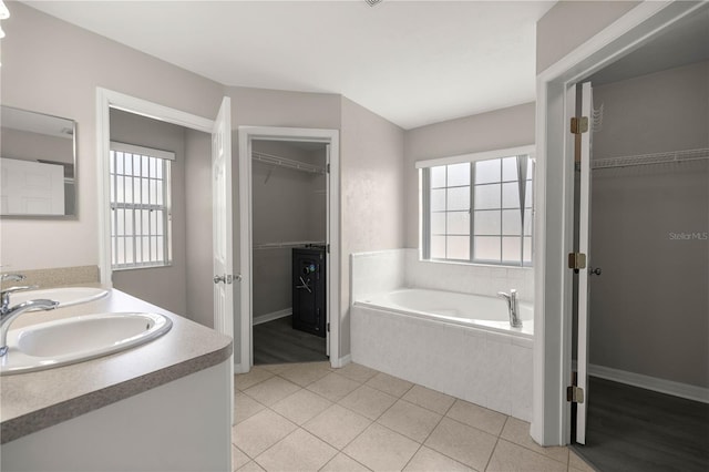 bathroom featuring vanity, tiled bath, tile patterned floors, and a healthy amount of sunlight