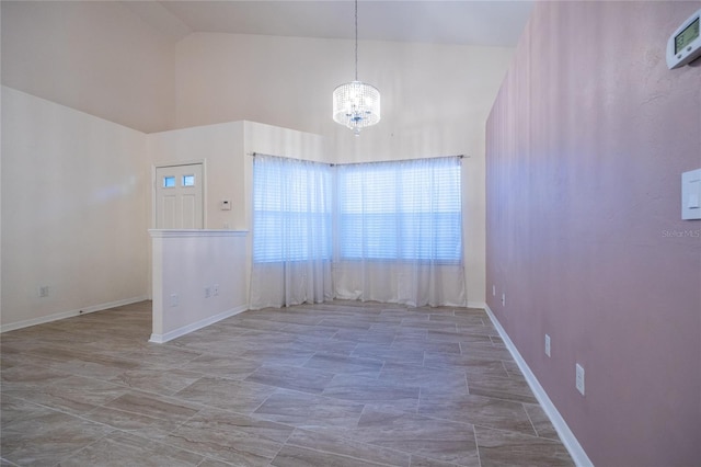 spare room with a notable chandelier and high vaulted ceiling