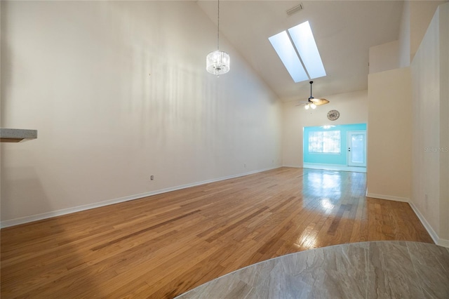 interior space featuring ceiling fan with notable chandelier, wood-type flooring, and high vaulted ceiling