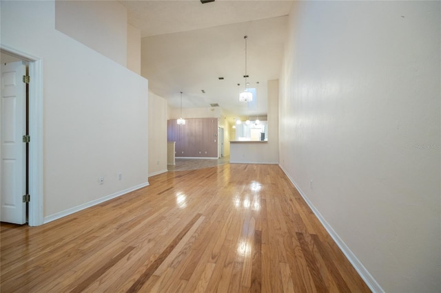 unfurnished living room featuring light hardwood / wood-style floors and a towering ceiling