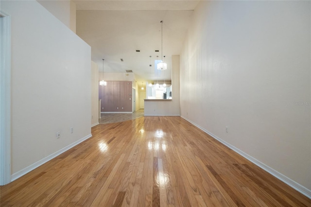 unfurnished living room with a high ceiling, light hardwood / wood-style flooring, and a notable chandelier