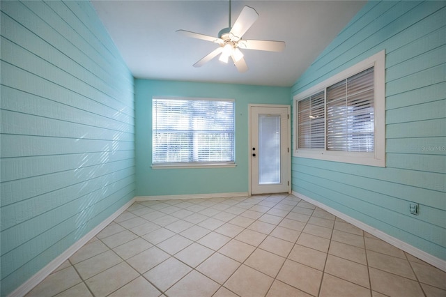 interior space featuring wood walls, ceiling fan, light tile patterned flooring, and lofted ceiling