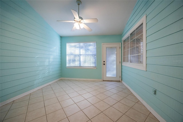 interior space featuring wood walls, light tile patterned floors, and ceiling fan