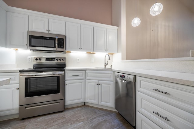 kitchen featuring white cabinetry, sink, decorative light fixtures, and appliances with stainless steel finishes