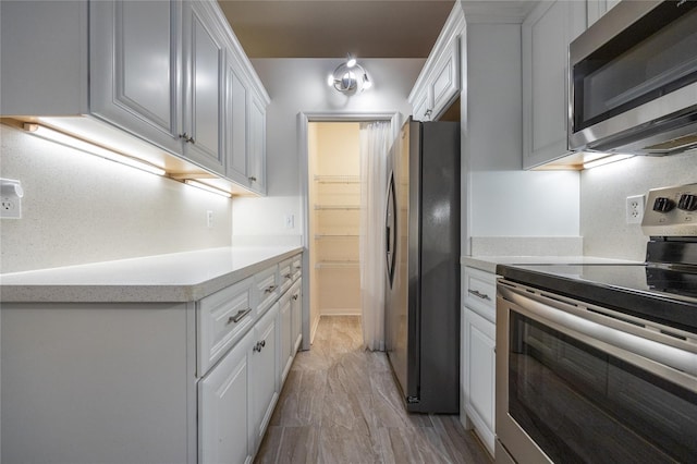 kitchen with white cabinets, appliances with stainless steel finishes, and light hardwood / wood-style floors