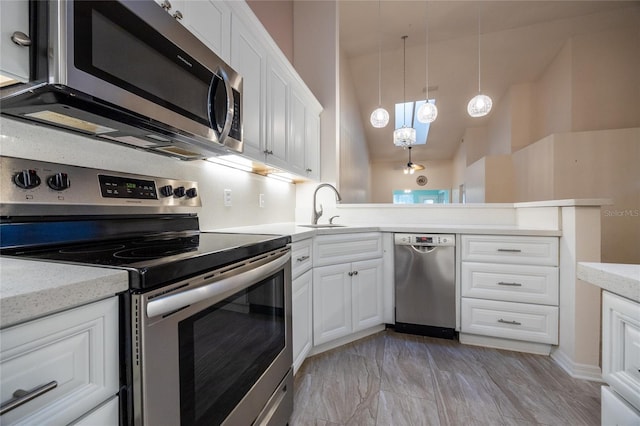 kitchen featuring white cabinets, sink, appliances with stainless steel finishes, decorative light fixtures, and kitchen peninsula