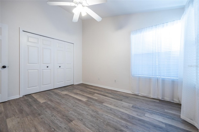 unfurnished bedroom featuring ceiling fan, dark hardwood / wood-style floors, lofted ceiling, and a closet