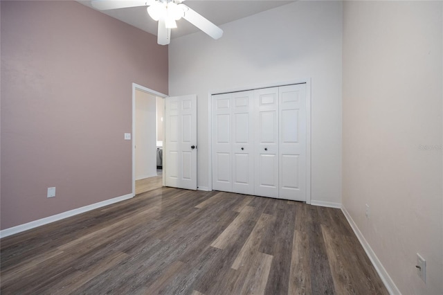 unfurnished bedroom featuring a high ceiling, dark hardwood / wood-style flooring, a closet, and ceiling fan