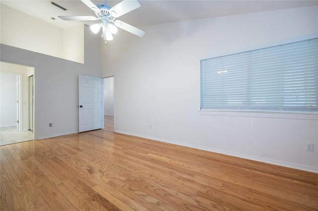 unfurnished room featuring ceiling fan, a towering ceiling, and light hardwood / wood-style flooring