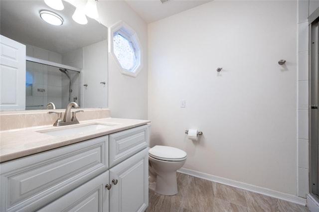 bathroom with a shower with door, vanity, and toilet