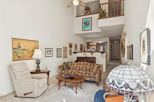 living room with carpet floors, a towering ceiling, and ceiling fan with notable chandelier