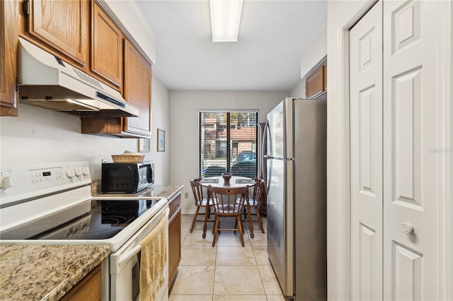 kitchen with light stone countertops, stainless steel fridge, light tile patterned floors, and electric stove