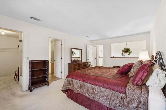 bedroom with a walk in closet, a closet, and light colored carpet