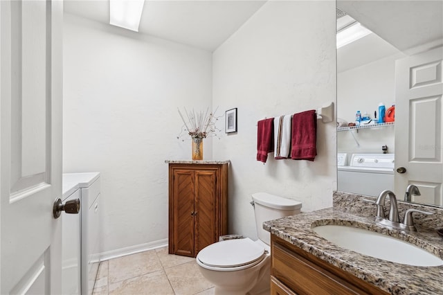 bathroom featuring tile patterned flooring, toilet, washing machine and dryer, and vanity