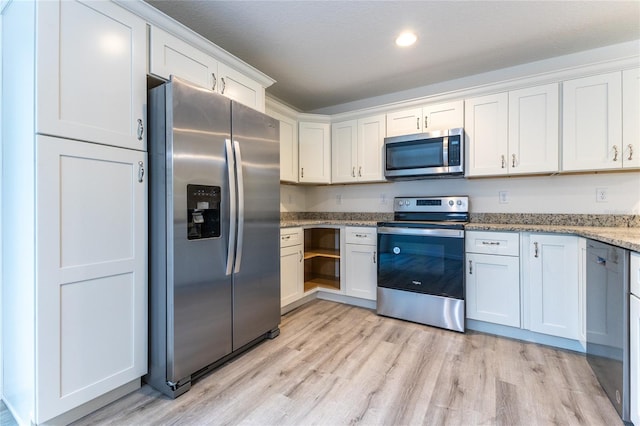 kitchen featuring light stone countertops, white cabinetry, light hardwood / wood-style flooring, and stainless steel appliances