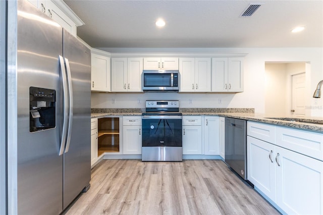 kitchen with white cabinets, light stone countertops, and stainless steel appliances