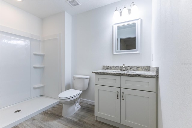 bathroom with hardwood / wood-style flooring, toilet, walk in shower, and vanity