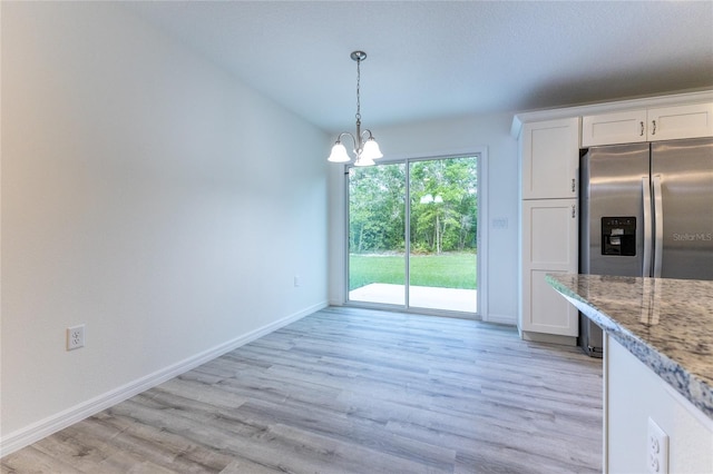 unfurnished dining area featuring a chandelier and light hardwood / wood-style flooring