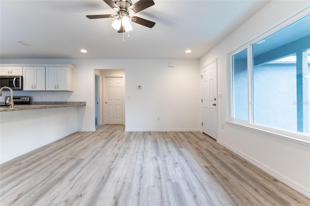 unfurnished living room featuring light hardwood / wood-style flooring and ceiling fan