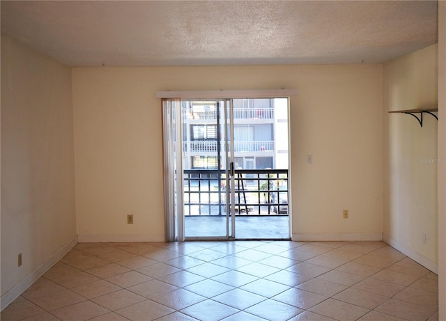 tiled empty room featuring a textured ceiling