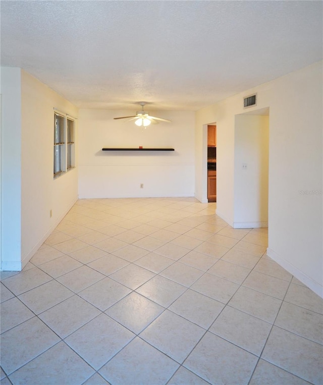 tiled empty room featuring a textured ceiling and ceiling fan