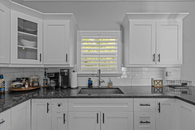 kitchen featuring sink, white cabinets, and dark stone counters