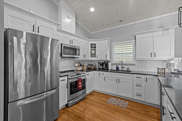 kitchen with white cabinets, stainless steel appliances, lofted ceiling, and sink