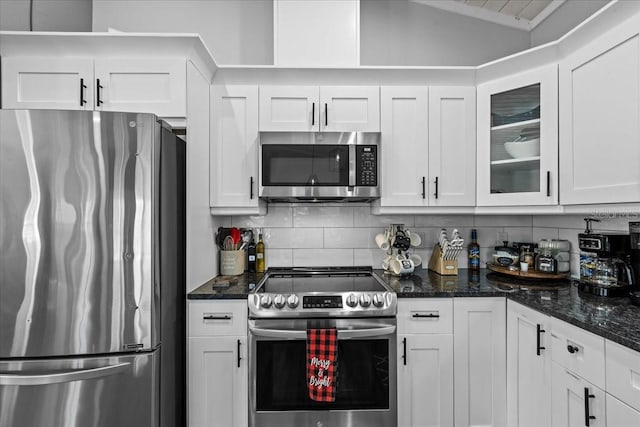 kitchen featuring tasteful backsplash, dark stone countertops, white cabinets, and stainless steel appliances