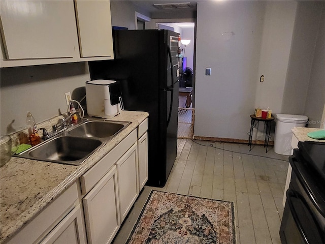 kitchen with light stone countertops, black range with electric cooktop, light wood-type flooring, and sink