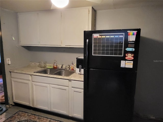 kitchen featuring black fridge, sink, and white cabinets