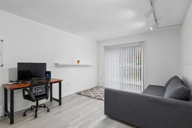 office area with rail lighting and light hardwood / wood-style floors