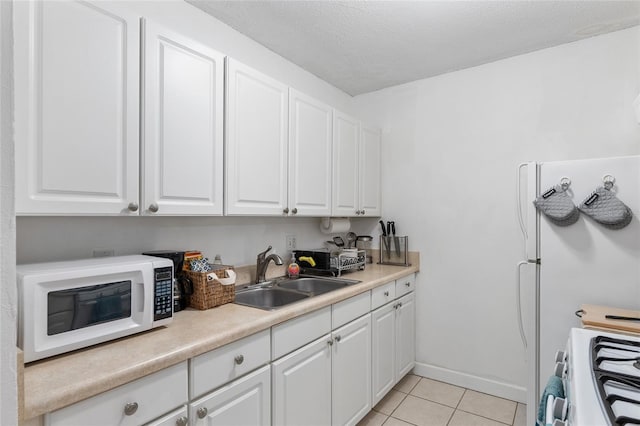 kitchen featuring white cabinets, light tile patterned floors, sink, and range