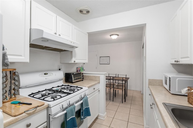 kitchen with white cabinets, white appliances, sink, and light tile patterned flooring