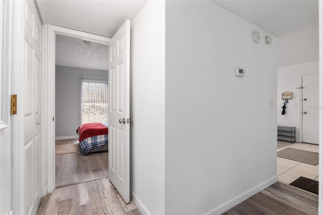 corridor featuring a textured ceiling and light hardwood / wood-style floors