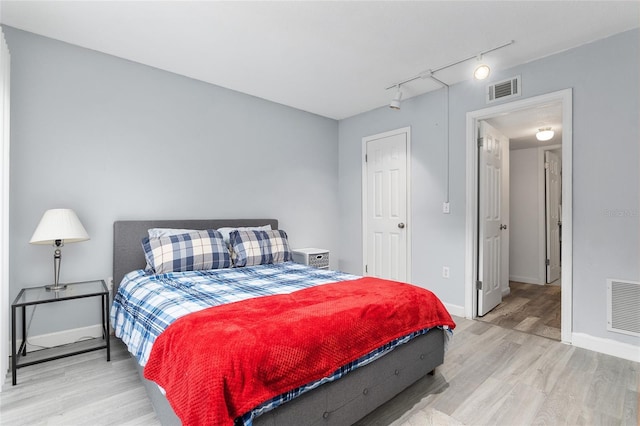 bedroom featuring rail lighting and light wood-type flooring