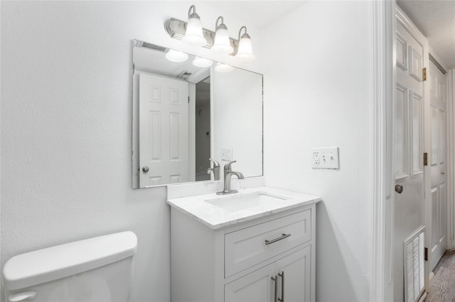 bathroom with vanity, toilet, and a textured ceiling