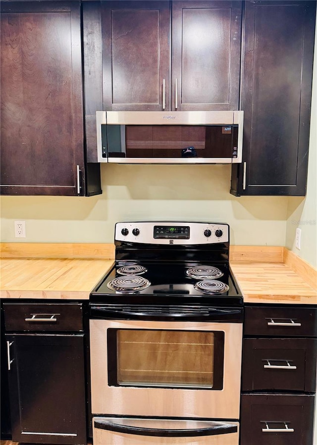 kitchen featuring stainless steel appliances, butcher block counters, dark brown cabinets, and exhaust hood