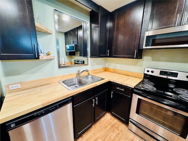 kitchen with appliances with stainless steel finishes, light hardwood / wood-style floors, sink, and wooden counters