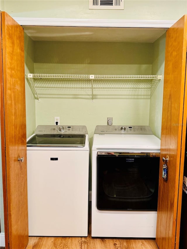 laundry room with washing machine and clothes dryer and light wood-type flooring