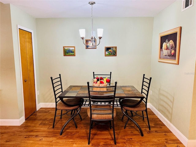 dining space with wood-type flooring and a chandelier