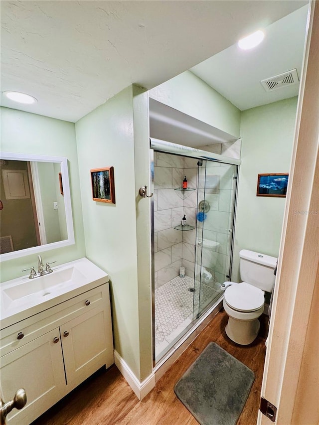 bathroom featuring a shower with door, wood-type flooring, vanity, and toilet