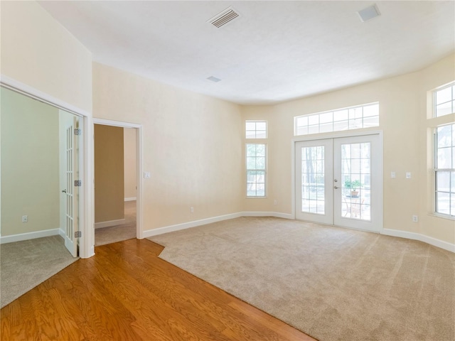 spare room featuring french doors and light hardwood / wood-style floors