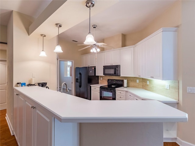 kitchen featuring tasteful backsplash, kitchen peninsula, white cabinets, and black appliances