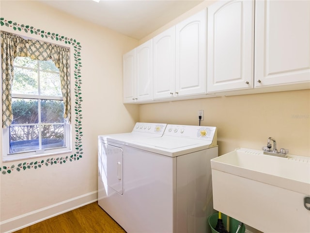 clothes washing area featuring washer and clothes dryer, sink, cabinets, and dark hardwood / wood-style floors