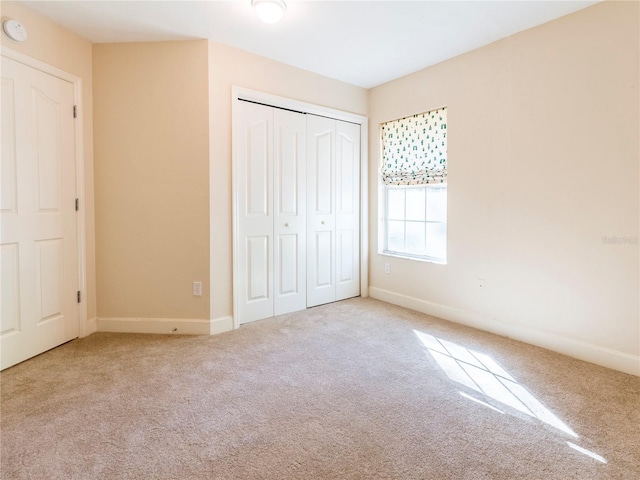 unfurnished bedroom featuring light colored carpet and a closet