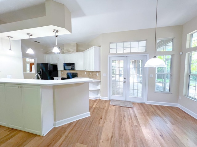 8305 SW 16th Pl, Gainesville, FL 32607 - kitchen with black appliances, light wood-style flooring, white cabinetry, backsplash, and a towering ceiling