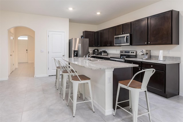 kitchen with sink, a kitchen bar, stainless steel appliances, and a kitchen island with sink