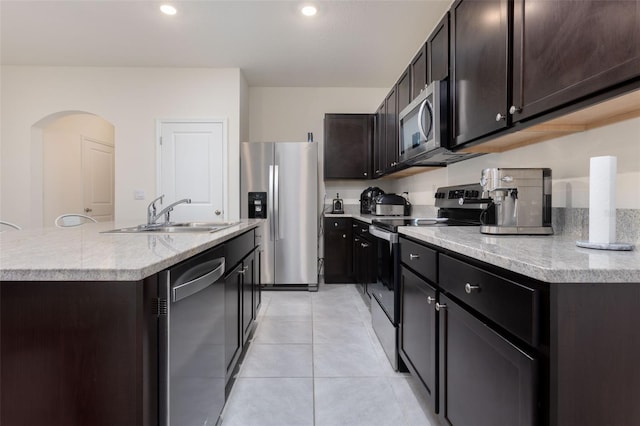 kitchen with sink, light tile patterned flooring, a center island with sink, and appliances with stainless steel finishes